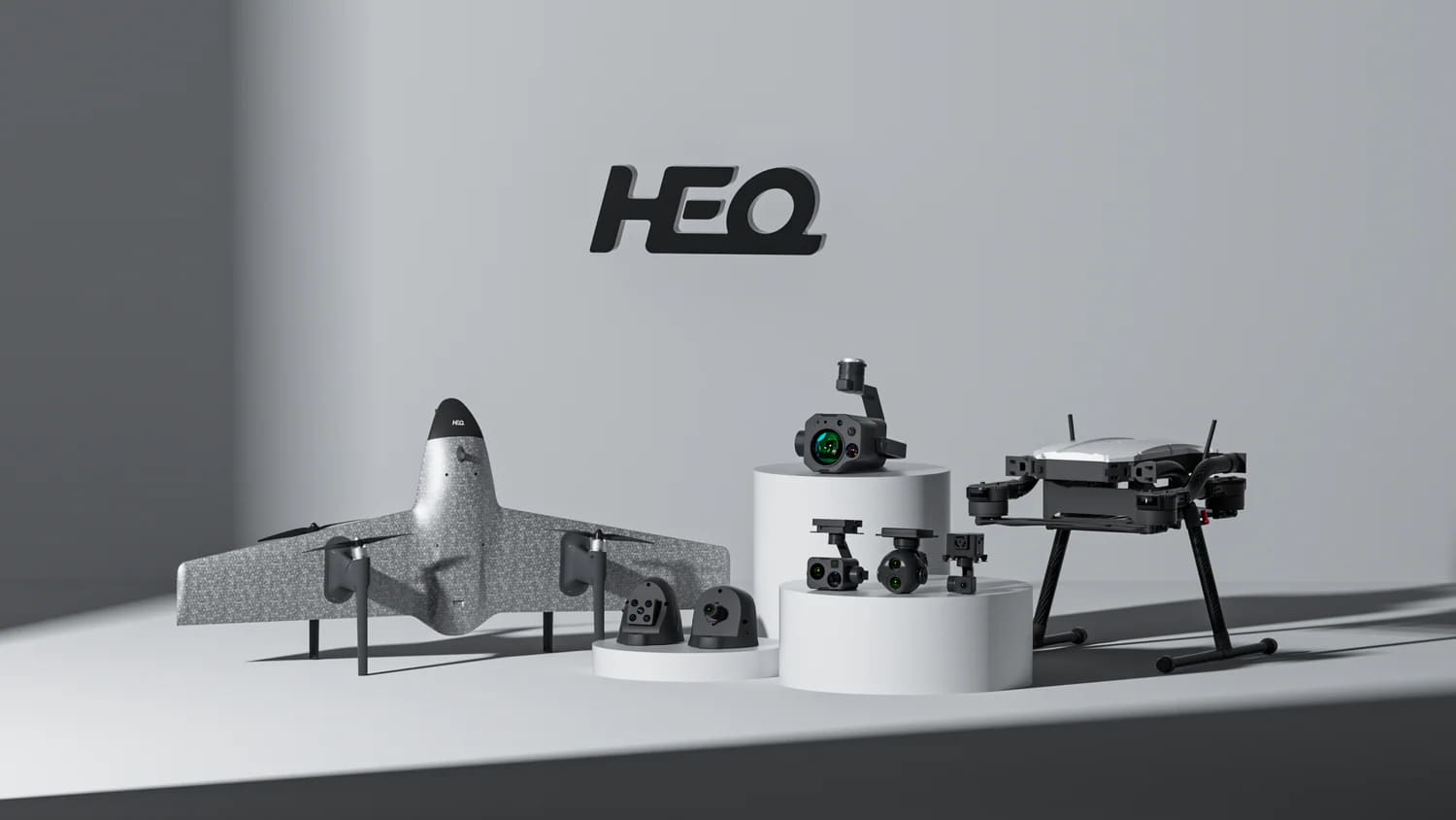 HEQ Product family featuring Swan serie drone, camera payloads and gimbals on a three pedestals with HEQ logo in back