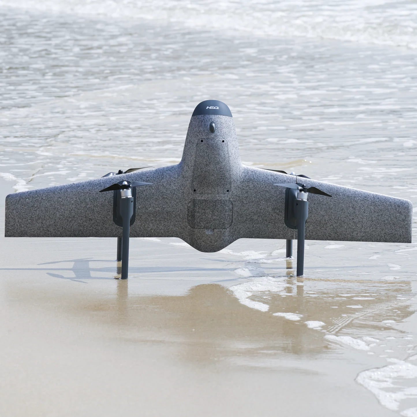 A silver HEQ drone with four propellers at the beach ready to take off