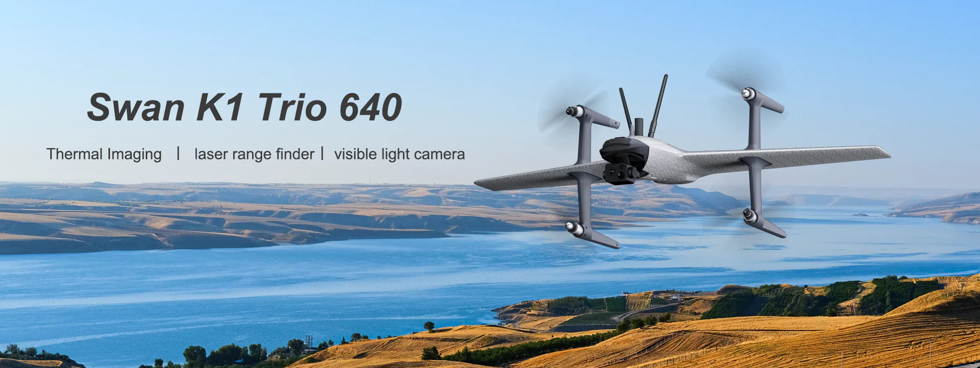A HEW Swan K1 Trio 640 drone fly in motion in air with green field, blue sea, and sky in the background.